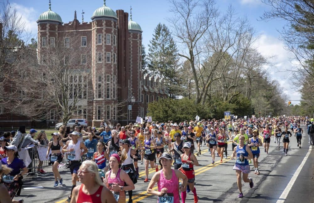 As the sun comes out toward the middle of the day, marathon runners race through the “scream tunnel” at Wellesley. (Robin Lubock/WBUR)