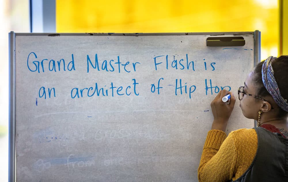 Kyara Andrade writes on a whiteboard during a workshop on hip-hop's founders this week. (Jesse Costa/WBUR)
