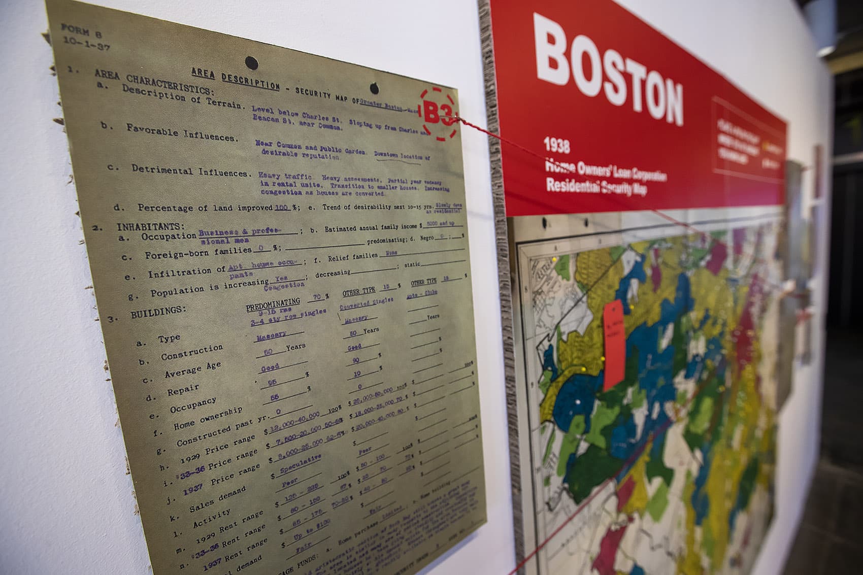 Documents and a map show examples of redlining in Boston in the "Undesign the Redline: the Transformation of Race, Place, and Class in America" exhibit at the Boston Architectural College. (Jesse Costa/WBUR)