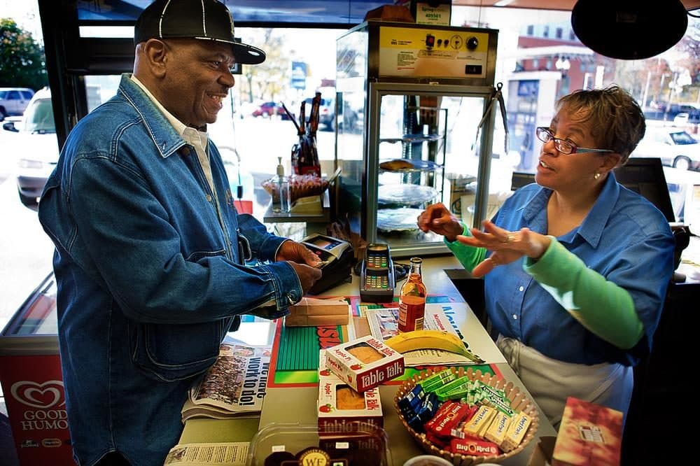 In this 2013 file photo, Stacey Thomas, right, works at the family’s Mobil Station on Blue Hill Avenue in Mattapan Square. (Jesse Costa/WBUR)