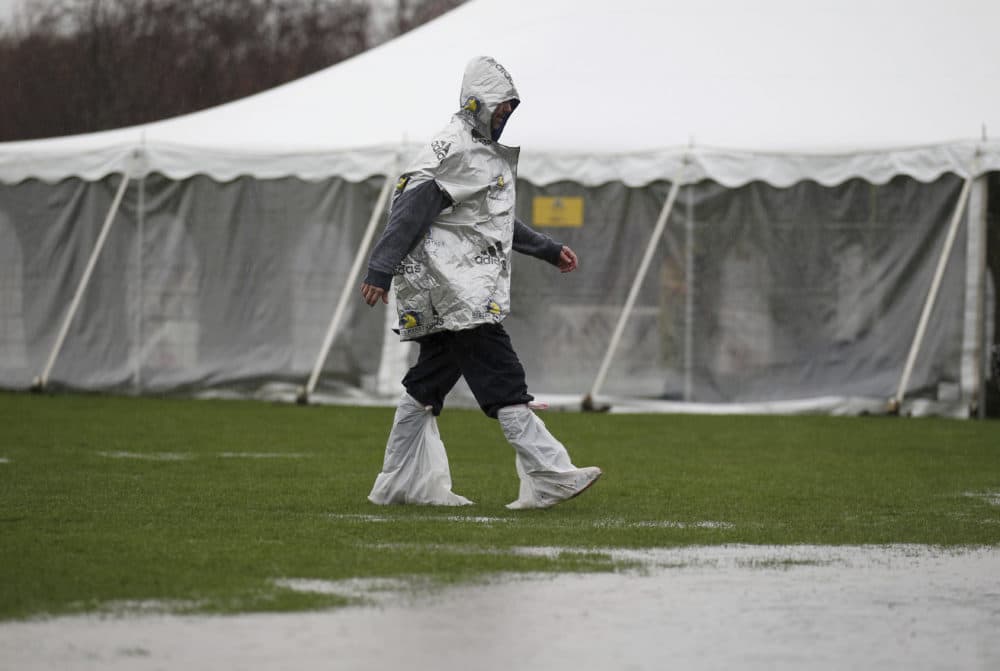 An unidentified runner navigates the flooded athletes village prior to the start of the 123rd Boston Marathon in Hopkinton. (Stew Milne/AP)