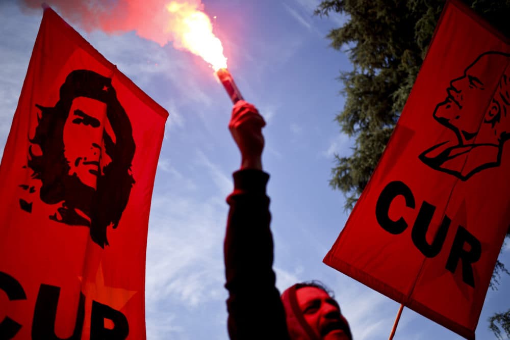 A man holds a flare, flanked by banners depicting Cuban revolutionary heroes Ernesto &quot;Che&quot; Guevara&quot; and Jose Marti, during the annual May Day march, in Santiago, Chile, May 1, 2018. (Esteban Felix/AP)