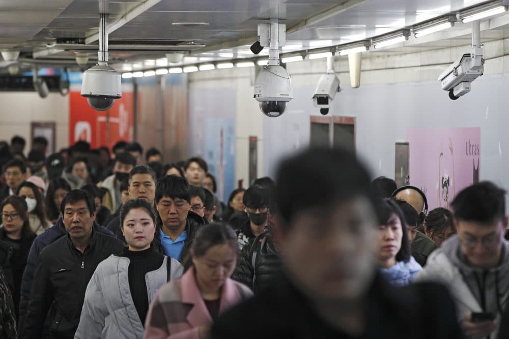 Commuters walk by surveillance cameras installed near a subway station in Beijing, Feb. 26, 2019. The Chinese government has used facial recognition and other technology to tighten control over society. (Andy Wong/AP)