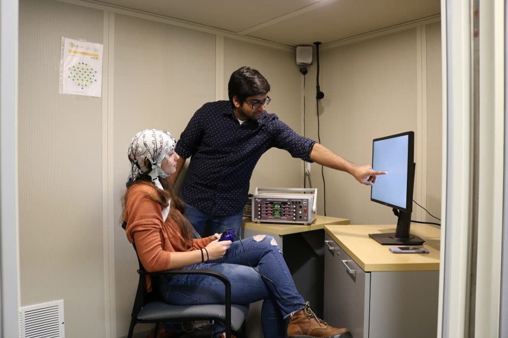 A young woman wears the skull cap with electrodes while performing a working memory test. (Courtesy of Rob Reinhart/BU)