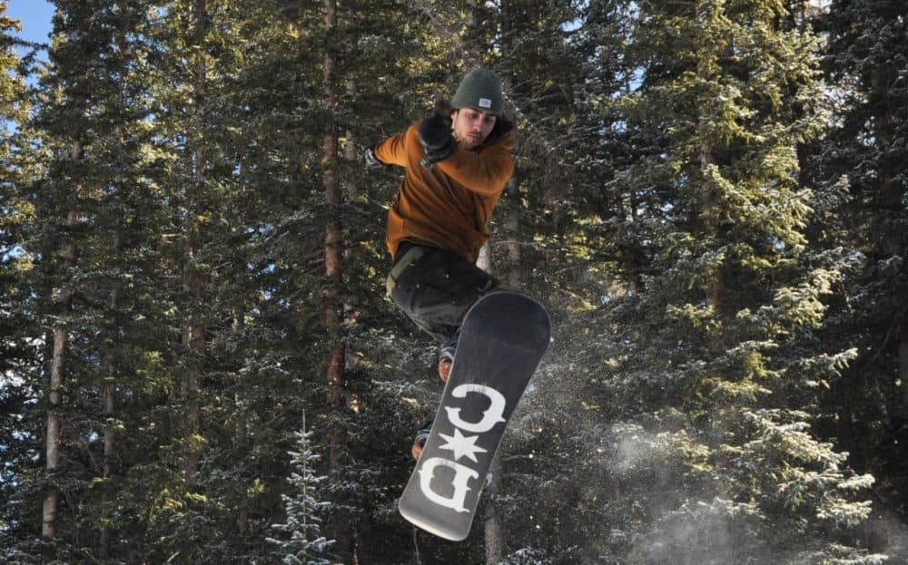 Avery Tate, 21, catches air off a rail built with spare lumber and PVC pipe in a park near Crested Butte, Colorado. (Durrie Bouscaren/Mountain West News Bureau)