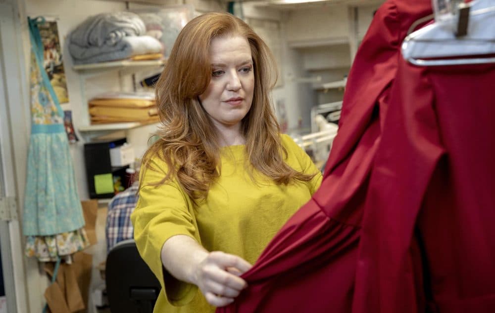 Jennifer Johnson Cano looks through handmaids' costumes on a visit to Costume Works Inc. in Boston. (Robin Lubbock/WBUR)