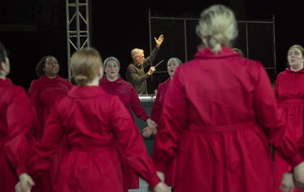 David Angus conducts as handmaids circle on the stage, at a rehearsal of &quot;The Handmaid's Tale.&quot; (Robin Lubbock/WBUR)