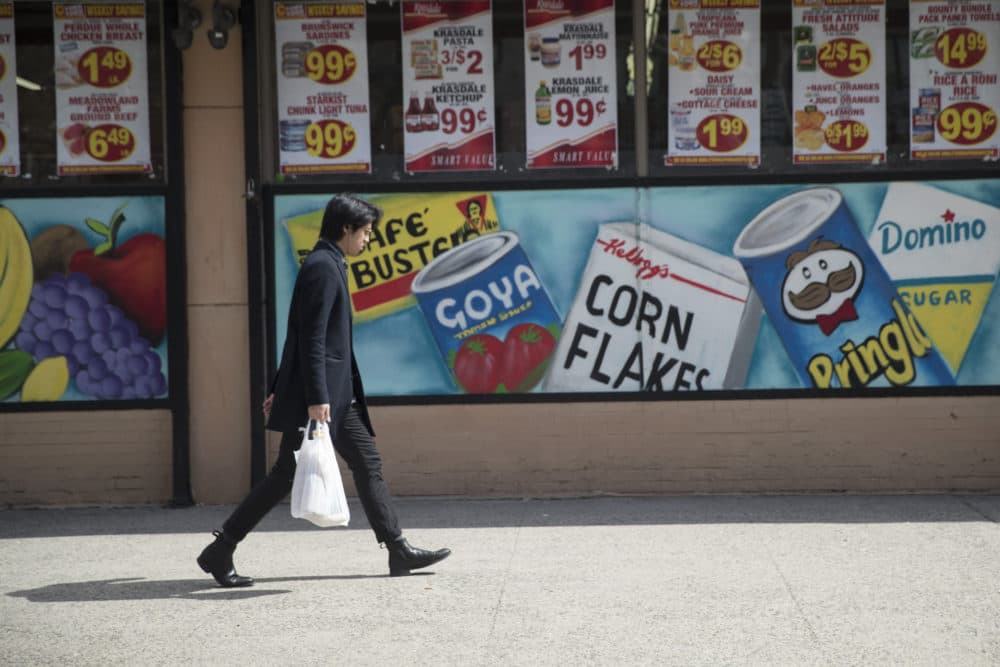 A man leaves a supermarket in the East Village neighborhood of Manhattan carrying his groceries in a plastic bag on March 27. (Mary Altaffer/AP)