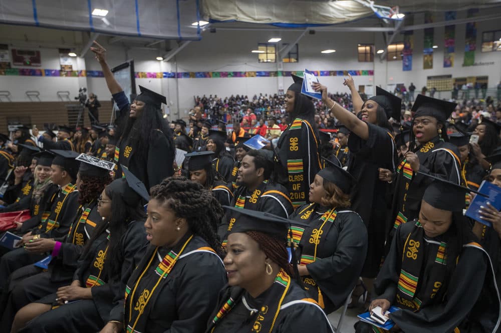 Roxbury Community College graduates cheer during one of the speeches given at the commencement. (Jesse Costa/WBUR)