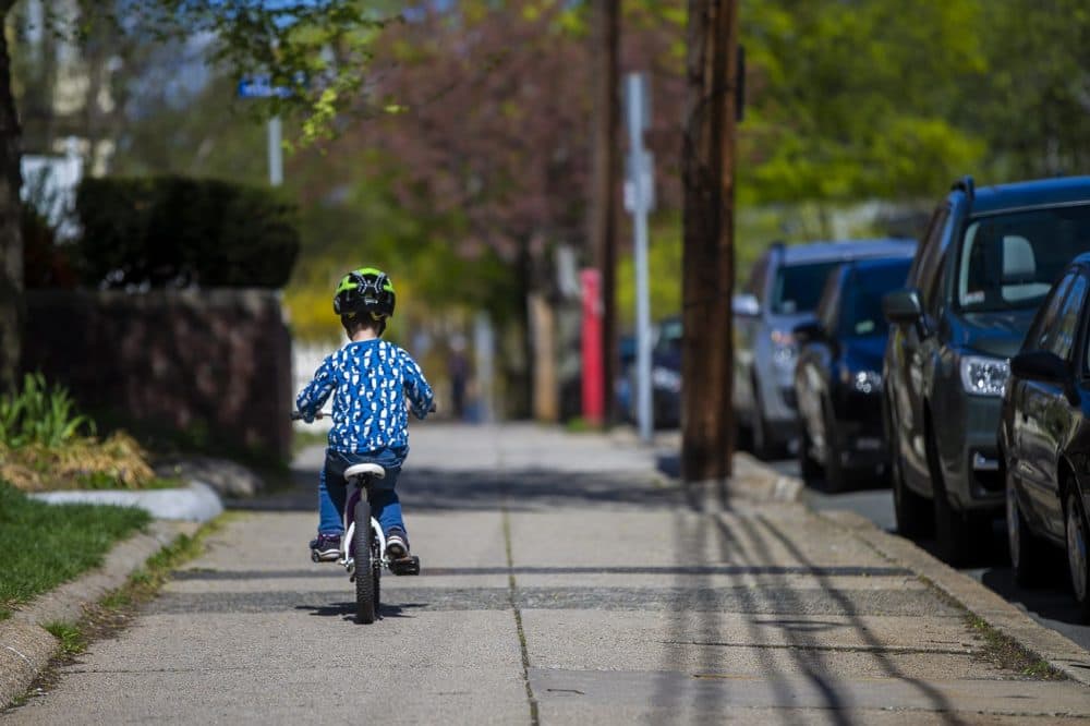 Ben rides his bike ahead of his mom on the sidewalk along College Avenue in Somerville. (Jesse Costa/WBUR)