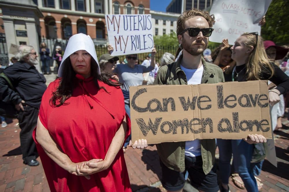 Laura Innis, left, made the trip to Boston from Falmouth dressed as a handmaiden from “The Handmaid’s Tale” to attend the rally. (Jesse Costa/WBUR)