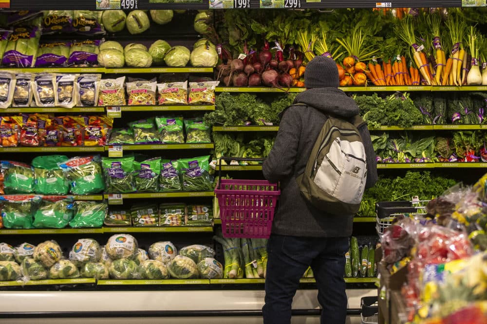 A customer peruses the produce at Roche Bros. in West Roxbury. (Jesse Costa/WBUR)