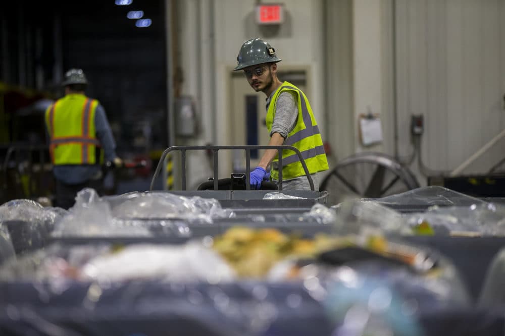 A worker moves a bin of discarded food from a Stop & Shop store before the food is processed and fed into the company's anaerobic digester. (Jesse Costa/WBUR)