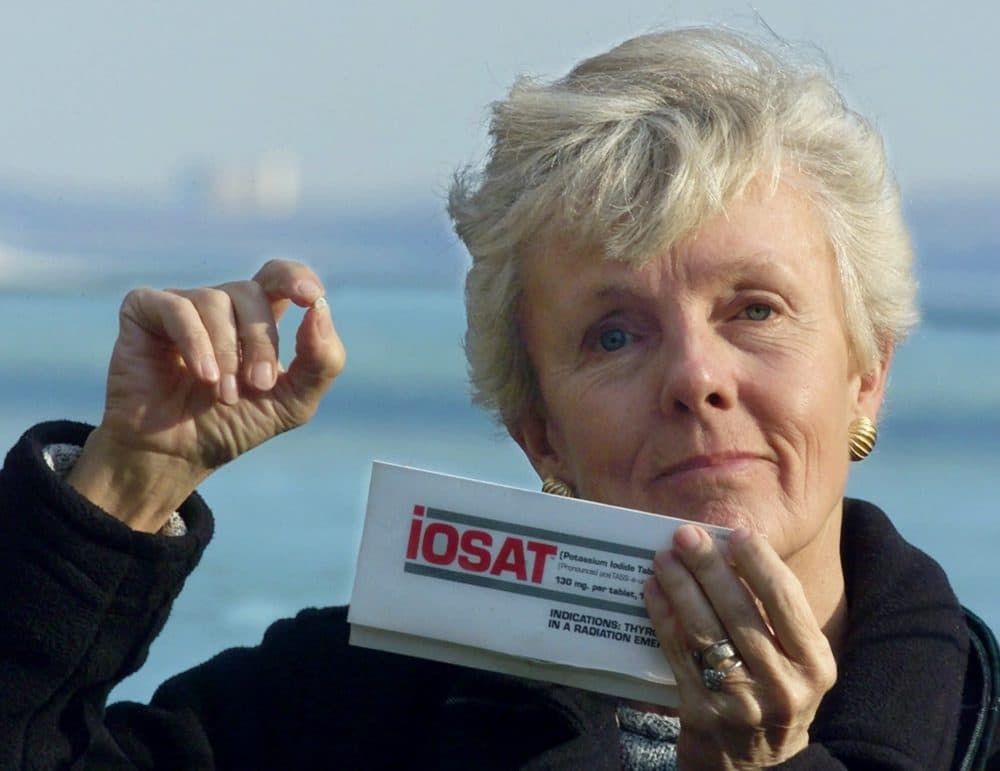 In this 2000 file photo, anti-Pilgrim activist Mary Lampert holds a tiny potassium iodine tablet in her Duxbury neighborhood, which overlooks the nuclear power plant. (Charles Krupa/AP)