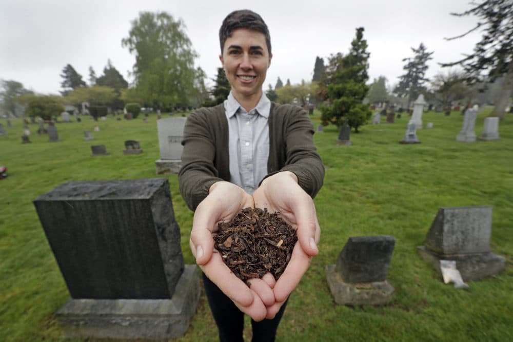 Katrina Spade, the founder and CEO of Recompose, displays a sample of the compost material left from the decomposition of a cow, using a combination of wood chips, alfalfa and straw, as she poses in a cemetery in Seattle. (Elaine Thompson/AP)