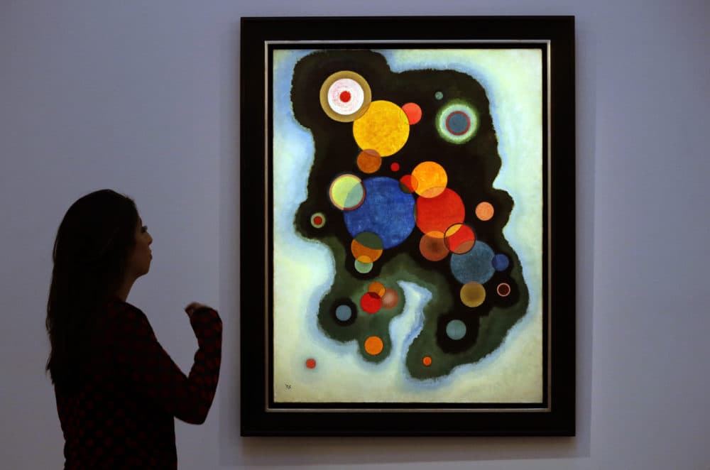 A Sotheby's employee looks at a painting by Wassily Kandinsky called 'Vertiefte Regung' (Deepened Impulse) at Sotheby's auction rooms in London, Feb. 20, 2019. (Kirsty Wigglesworth/AP)