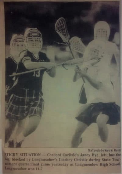 A newspaper clipping showing Longmeadow girls’ lacrosse players donning youth ice hockey helmets. (Courtesy Kathy Tomassetti)
