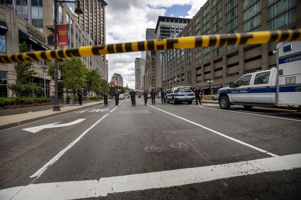 Boston police officers comb Huntington Avenue for additional evidence following a shooting in front of the Colonnade Hotel. (Jesse Costa/WBUR)