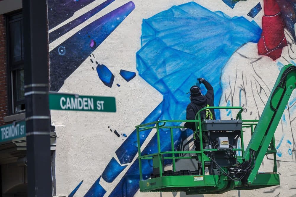 Artist Rob &quot;ProBlak&quot; Gibbs works on his latest mural, &quot;Breathe Life,&quot; on the side of 808 Tremont St. a three story building in Roxbury. (Jesse Costa/WBUR)