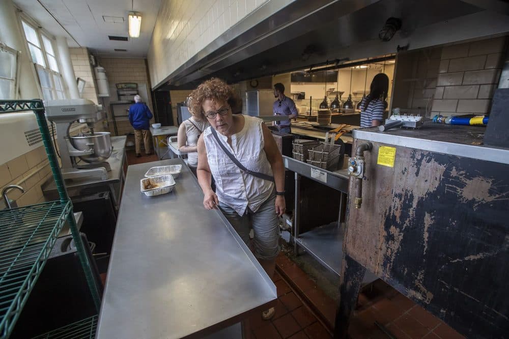 An interested buyer examines some stainless steel kitchen work tables in one of the kitchens at Newbury College. (Jesse Costa/WBUR)