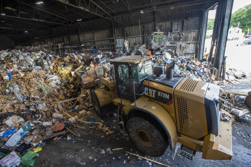 At E.L. Harvey &amp; Sons in Westborough, two land movers push about 1,000 tons of trash into the rear of a warehouse to be baled, packed and shipped out across the country. (Jesse Costa/WBUR)