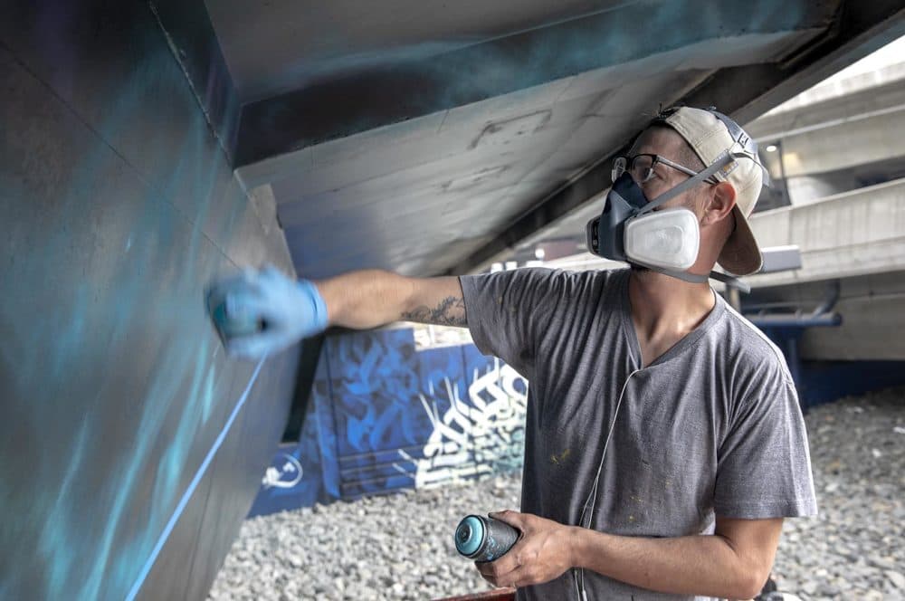 Dana Woulfe works on a mural at Underground at Ink Block. (Robin Lubbock/WBUR)