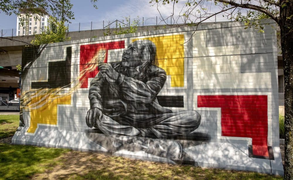 Go Five's mural seen in dappled sunlight under the trees beside I-93. (Robin Lubbock/WBUR)