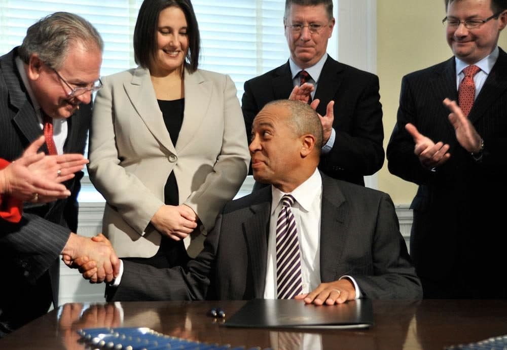 As others look on, then-Gov. Deval Patrick shakes hands with House Speaker Robert DeLeo after signing a bill legalizing casino gambling in Massachusetts in 2011. (AP) 