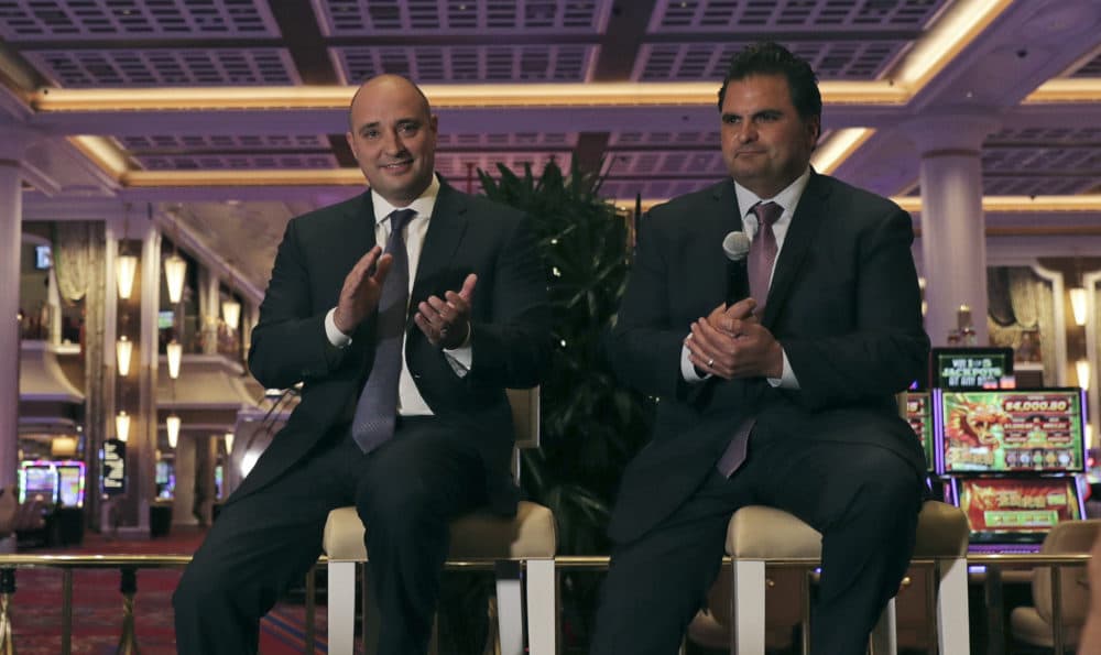 Wynn Resorts CEO Matthew Maddox, left, applauds while seated near the casino floor with Everett, Mass., Mayor Carlo DeMaria, right, at the Encore Boston Harbor casino in Everett, Mass., during a press tour June 21, 2019. (Charles Krupa/AP)