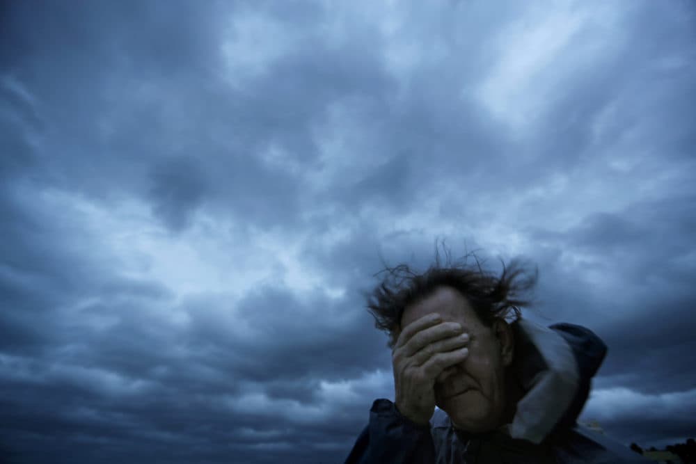 In this Friday, Sept. 14, 2018 file photo, Russ Lewis covers his eyes from a gust of wind and a blast of sand as Hurricane Florence approaches Myrtle Beach, S.C. (David Goldman/AP)