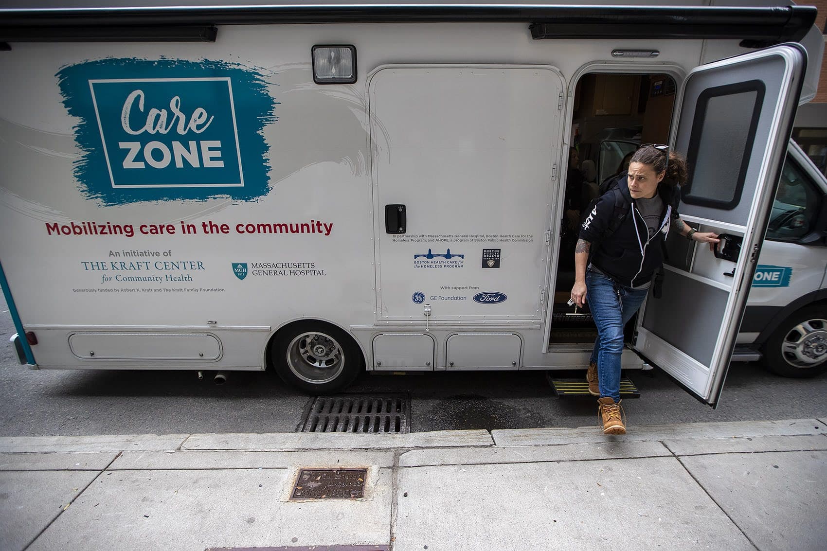 Sarah Mackin exits the Care Zone van after it parks on Haverhill Street near North Station. The outreach workers will mobilize and walk around the area to look for opioid users who need assistance. (Jesse Costa/WBUR)