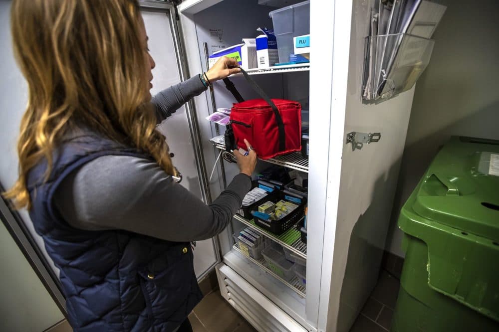Dr. Jessie Gaeta grabs vaccines that are stored in a refrigerator at the Healthcare for the Homeless office before being loaded onto the Care Zone van. (Jesse Costa/WBUR)
