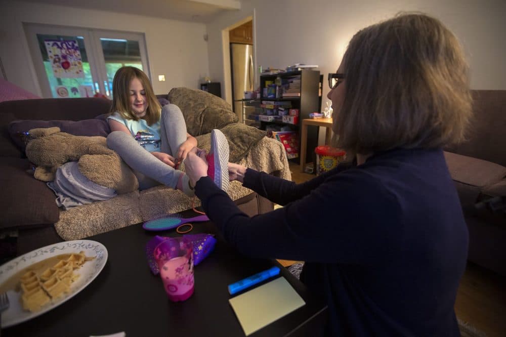 Heres helps Anya with getting her shoes on. (Jesse Costa/WBUR)