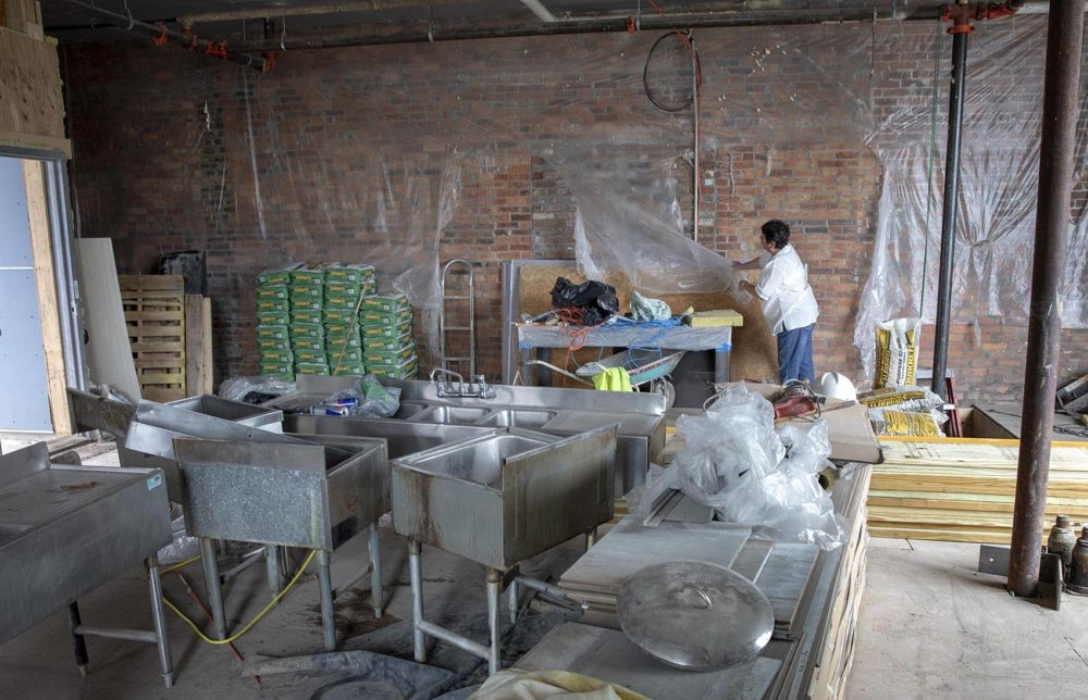 Darlene Casey looks behind the plastic sheeting used to cover the names on the wall of the former Fran's Place. (Robin Lubbock/WBUR)