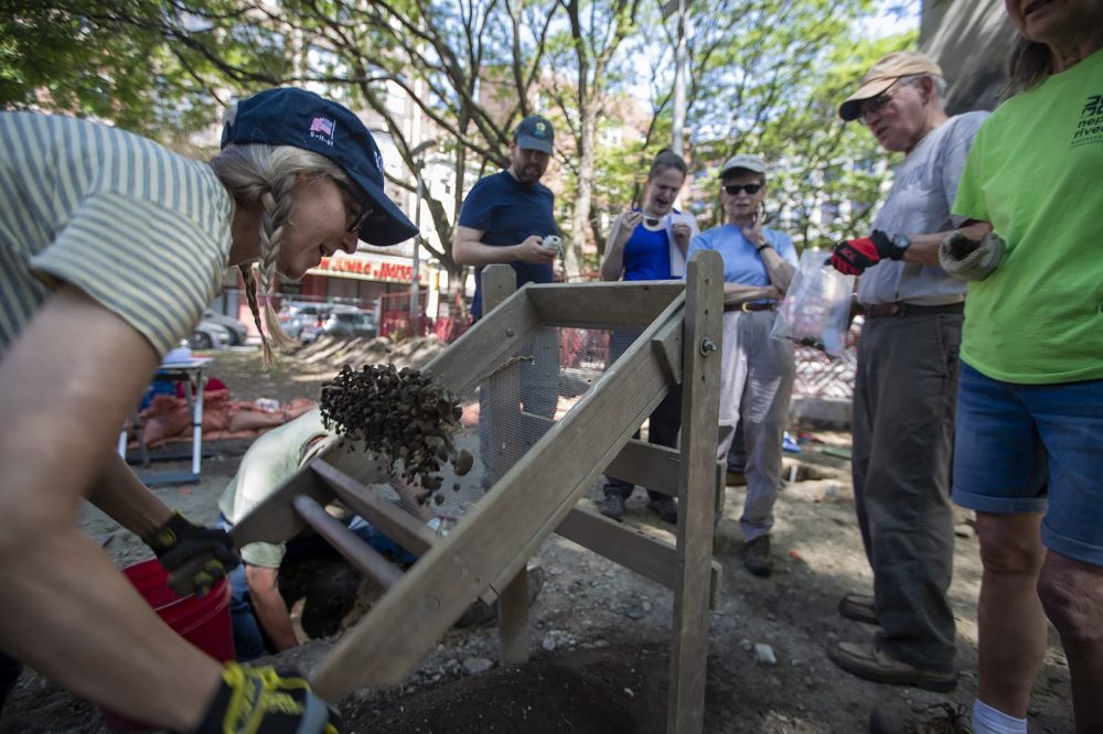 Volunteer Suzie Berlin dumps a load of rocks and debris from a soil sifter after the sample was examined for artifacts. (Jesse Costa/WBUR)