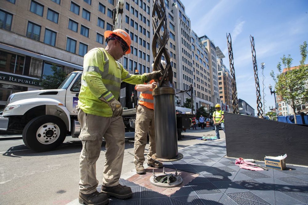 Installation workers place the final of four bronze towers into place at the site of the Boston Marathon bombing memorial on Boylston Street. (Jesse Costa/WBUR)