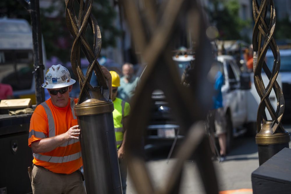 Installation worker Paul Beaulieu maneuvers an airborne tower suspended by a crane toward the location of its mount. (Jesse Costa/WBUR)