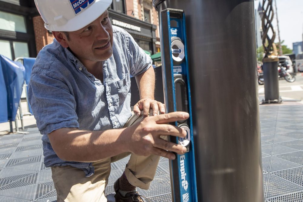 Artist Pablo Eduardo checks how straight the second tower is with a level. (Jesse Costa/WBUR)