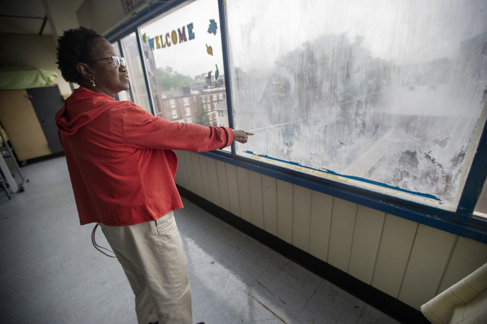 Anita Moore, interim principal of Jackson Mann K-8 School, points out damage caused by leaking windows. (Jesse Costa/WBUR)