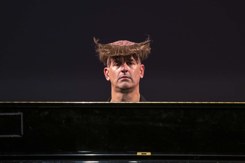 Comedian Joel Jeske's wig flips up from behind after he sneezes. (Jesse Costa/WBUR)