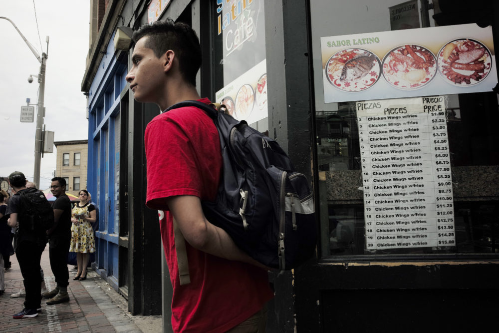 People prepare to board a bus outside a Latin-style cafe, right, in Chelsea, Mass. (Steven Senne/AP)
