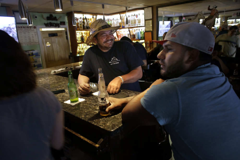 Patrons, who asked that they not be identified by name, are seated in a bar, in Chelsea, Mass. In the last two decades Chelsea and its neighbors Everett, Malden, Revere and Lynn have all become the region's most diverse communities, a Boston Indicators study found. (Steven Senne/AP)