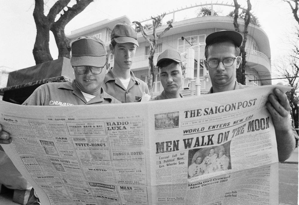 From left: U.S. Air Force Sgt. Michael Chivaris, Clinton, Mass.; Army Spec. 4 Andrew Hutchins, Middlebury, Vt.; Air Force Sgt. John Whalin, Indianapolis, Ind.; and Army Spec. 4 Lloyd Newton, Roseburg, Ore., read a newspaper about the Apollo 11 moon landing, in Saigon, Vietnam. (Hugh Van Es/AP)