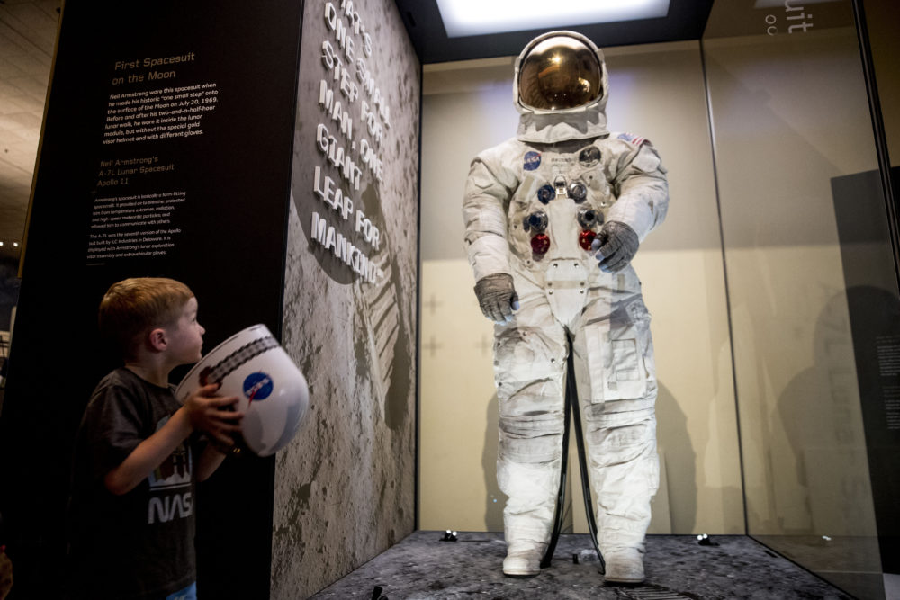 Jack Heely, 5, of Alexandria, Va., plays with a toy space helmet as he views Neil Armstrong's Apollo 11 spacesuit after it is unveiled at the Smithsonian's National Air and Space Museum on July 16, 2019. (Andrew Harnik/AP)