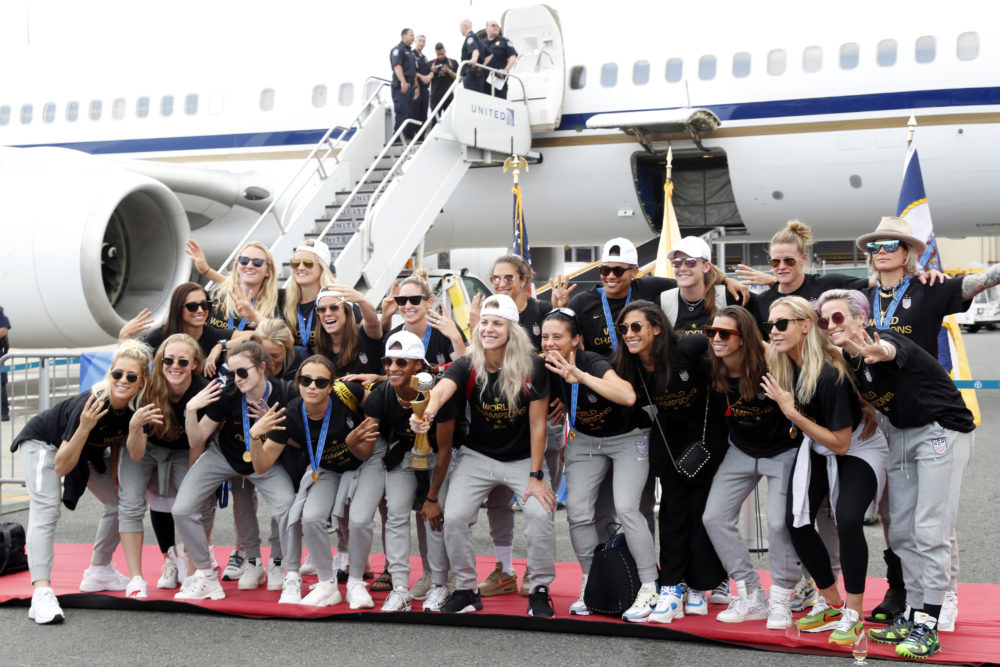 Members of the United States women's soccer team celebrate and pose with the World Cup trophy by their plane after arriving at Newark Liberty International Airport Monday. (Kathy Willens/AP)