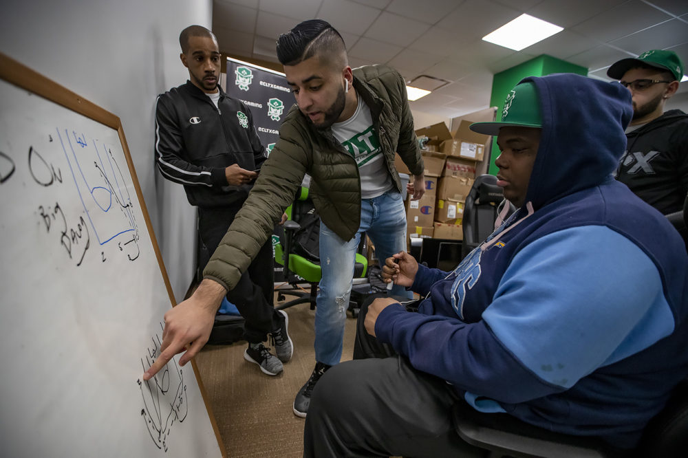 The Celtics Crossover Gaming team huddles around a whiteboard to discuss strategy. (Jesse Costa/WBUR)
