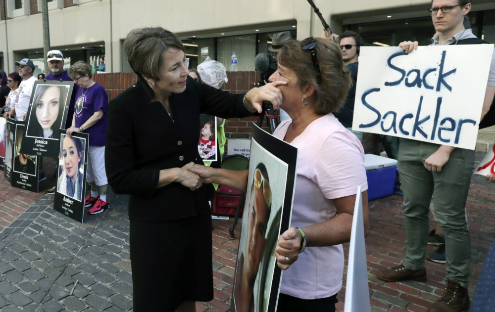Massachusetts Attorney General Maura Healey, left, wipes a tear from the face of Wendy Werbiskis, of Easthampton, Mass., one of the demonstrators gathered outside the courthouse in Boston. (Charles Krupa/AP)