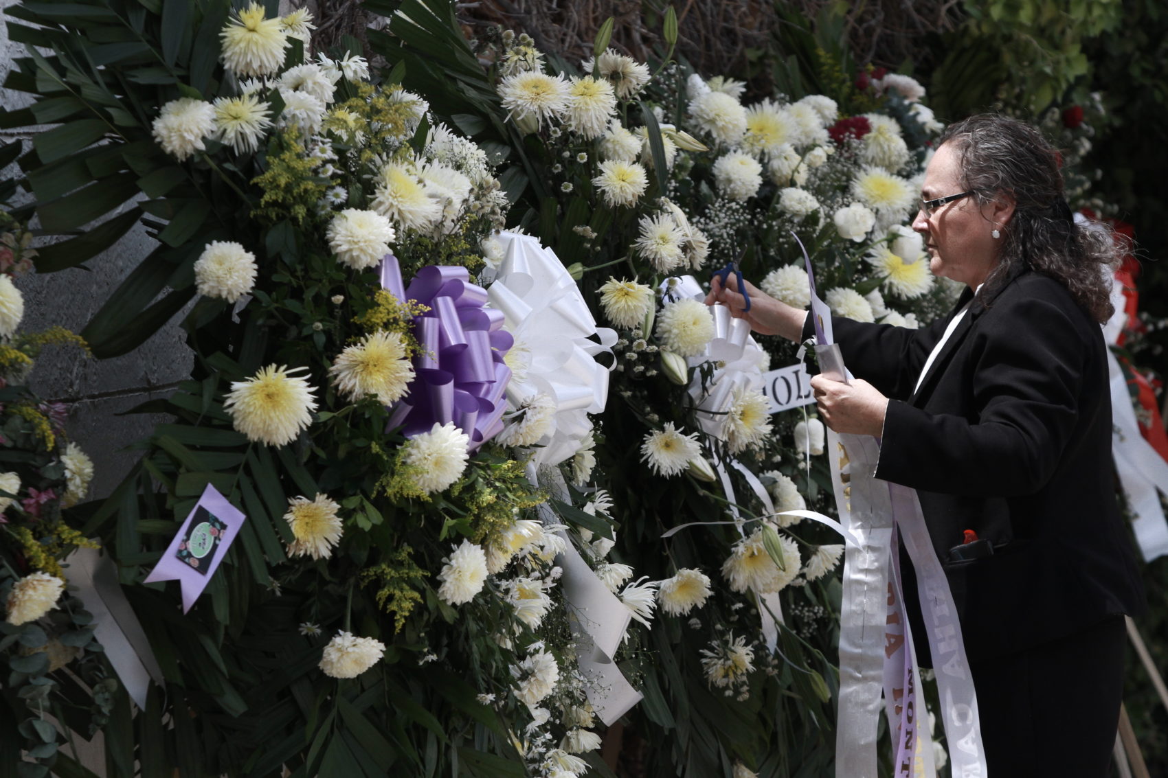 A woman places a ribbon on a flower arrangement, at the funeral of elementary school principal Elsa Mendoza, of one of the 22 people killed in a shooting at a Walmart in El Paso, in Ciudad Juarez, Mexico, on Aug. 8. (Christian Chavez/AP)