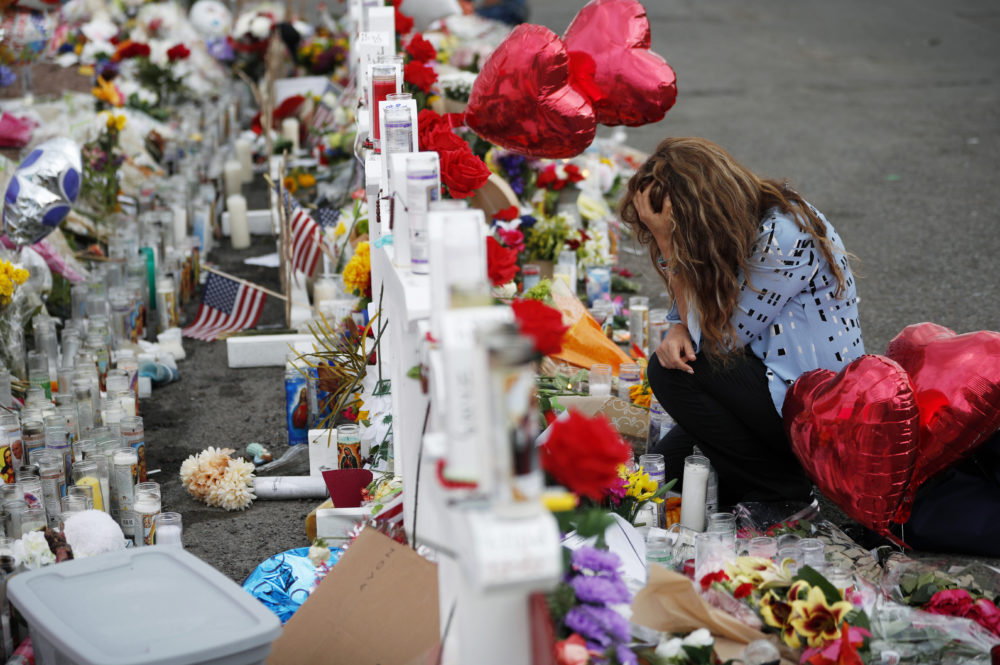 Gloria Garces kneels in front of crosses at a makeshift memorial near the scene of a mass shooting at a shopping complex Tuesday, Aug. 6, 2019, in El Paso, Texas. (AP/John Locher)