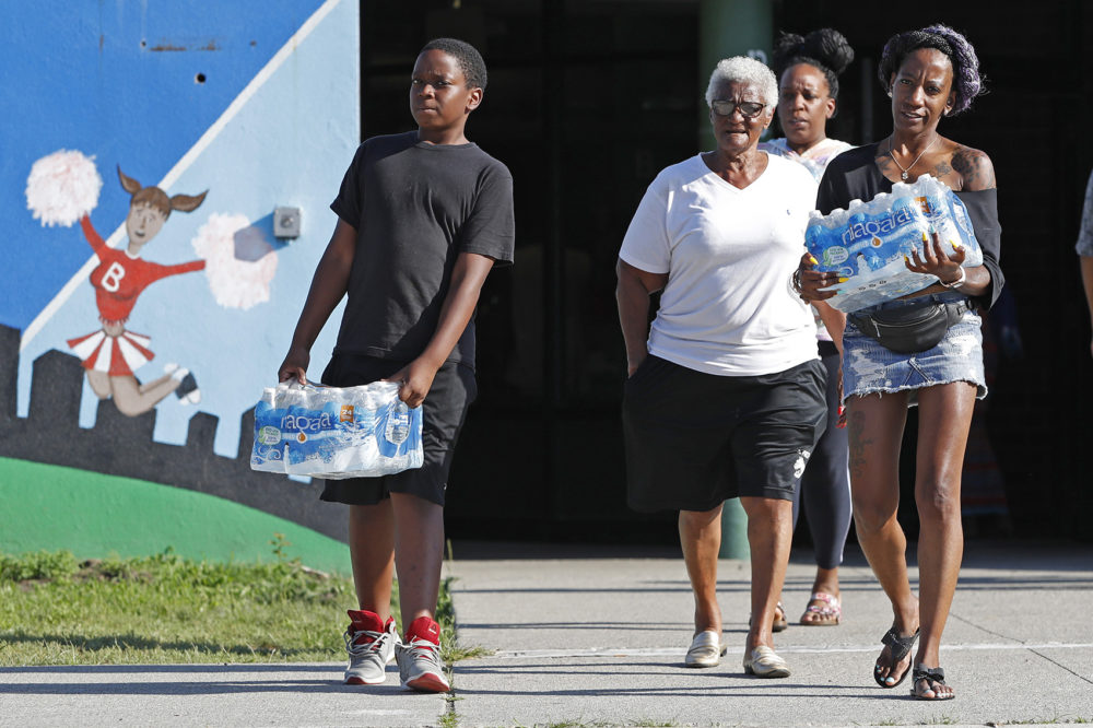 Rahjiah McBride, of Chester, Pa., right, helps her relatives, Newark residents Elnora and Bowdell Goodwin, center and second right, as Goodwin's son pitches in carrying bottled water from the Boylan Street Recreation Center, Monday, Aug. 12, 2019, in Newark, N.J. (Kathy Willens/AP)